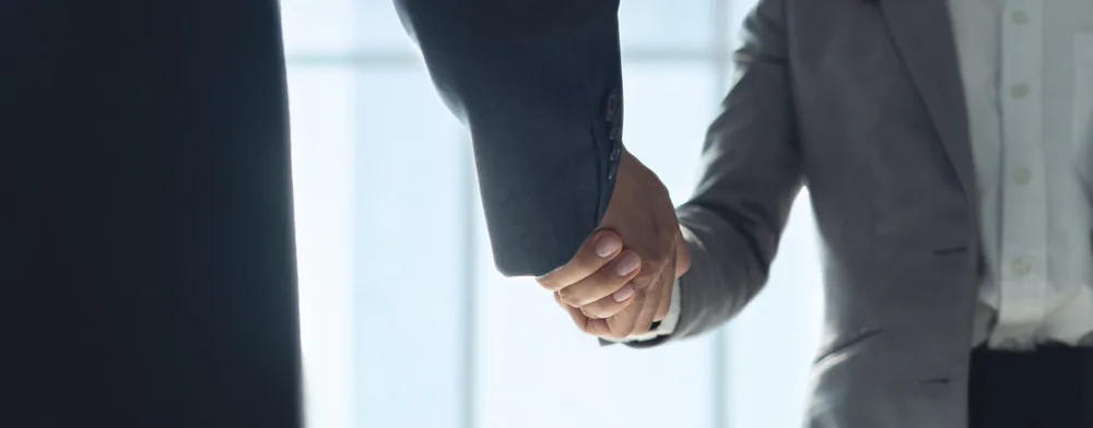 スーツ姿の2人が握手している手元
