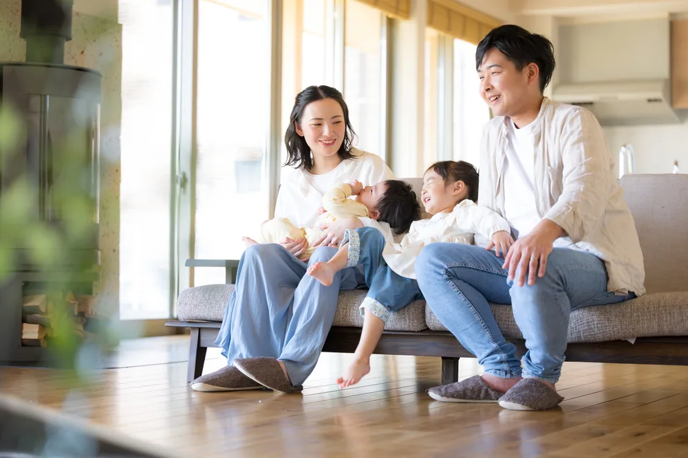 ソファに座って笑顔で過ごす父親と母親、赤ちゃん、女の子